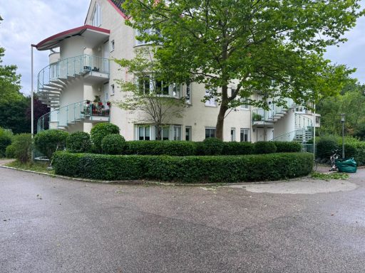 Garten- & Anlagenpflege – PS Hausmeisterservice Gepflegte Grünanlage mit geschnittenen Hecken und Bäumen vor einem Wohngebäude.