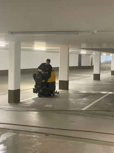 Professionelle Tiefgaragenreinigung Chef reinigt eine Tiefgarage mit einer Aufsitz-Scheuersaugmaschine.